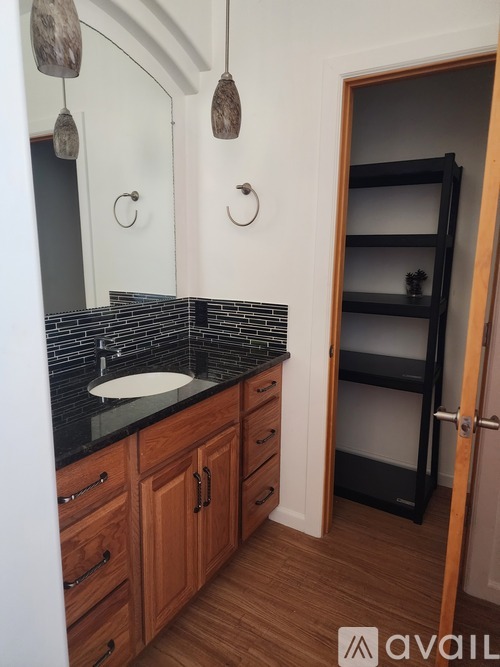 A bathroom with a sink, mirror, and wooden cabinets.