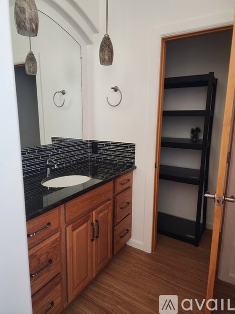 A bathroom with a sink, mirror, and wooden cabinets.