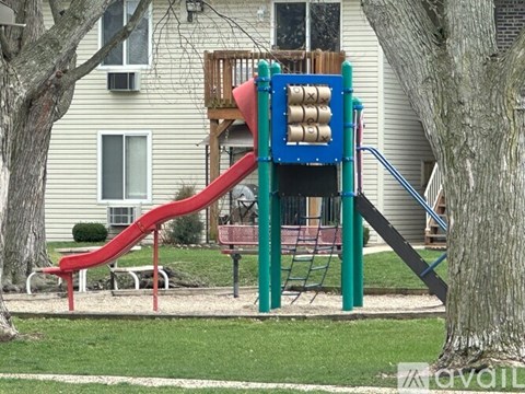 A playground with a red slide and a green and blue climbing structure.
