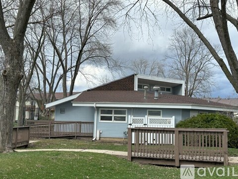 A house with a brown roof and a blue exterior is surrounded by trees.