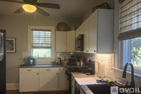 A kitchen with white cabinets and a black fridge.