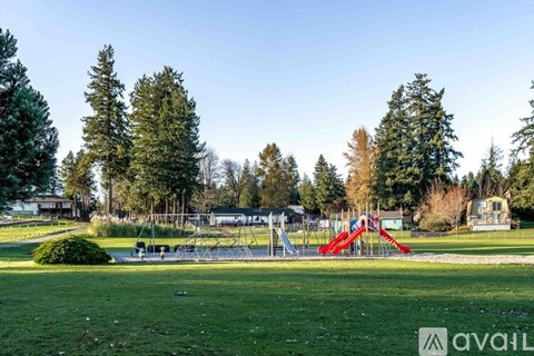 A playground with a red slide is surrounded by trees.