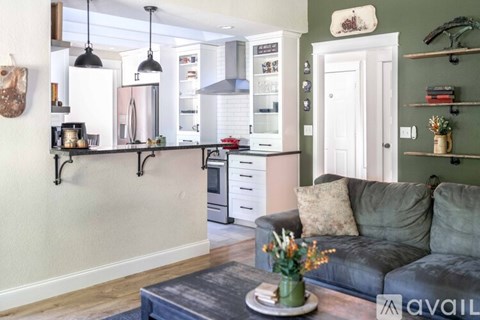 A kitchen with a grey couch and a coffee table in front of it.