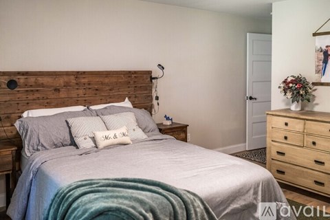 A bedroom with a bed, nightstand, and a wooden headboard.