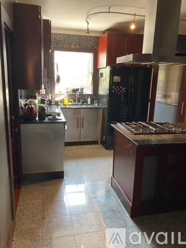 A kitchen with a black fridge and a black stove top.