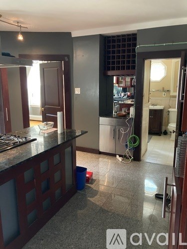 A kitchen with a dark counter top and a blue bucket on the floor.