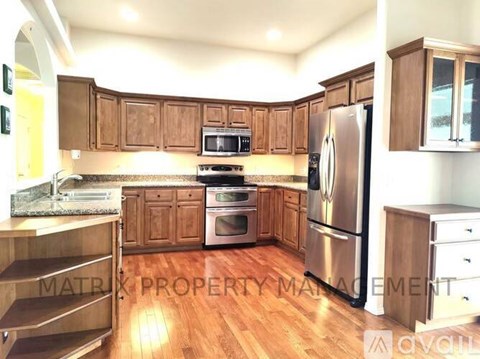 A kitchen with wooden cabinets and a stainless steel refrigerator.