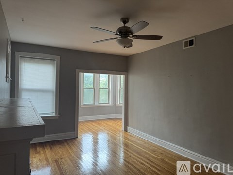 A room with a ceiling fan and wooden floors.