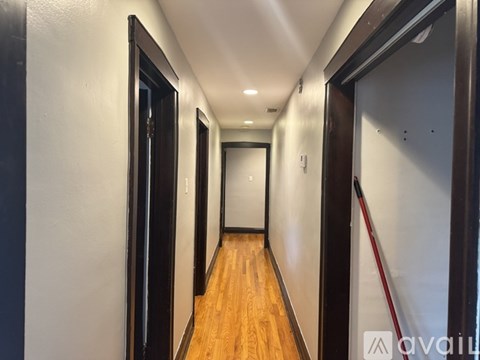 A long hallway with wood floors and white walls.
