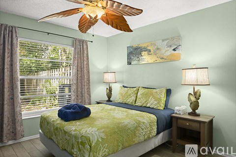 A bedroom with a bed, two lamps, and a ceiling fan.