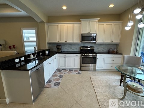 A kitchen with white cabinets and black countertops.