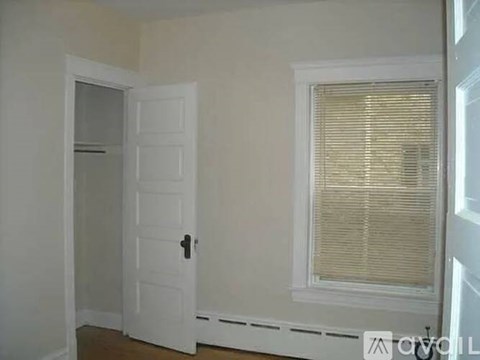 A white door with a black handle is on the left and a window with blinds is on the right.