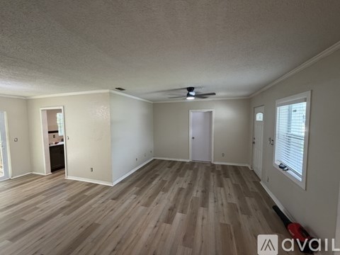 A spacious room with wooden flooring and a ceiling fan.