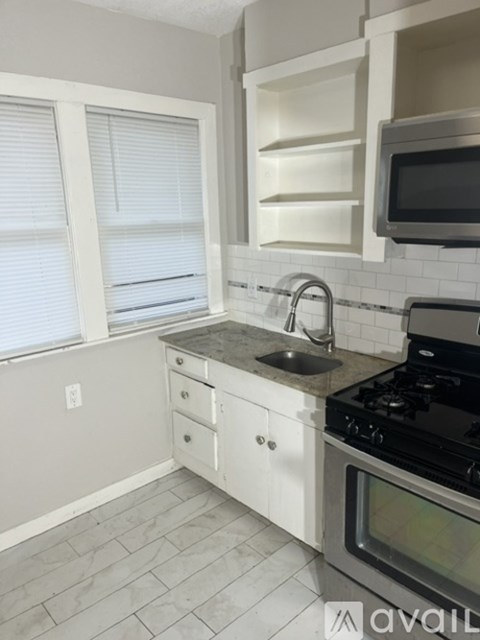 A kitchen with white cabinets and a black stove top oven.