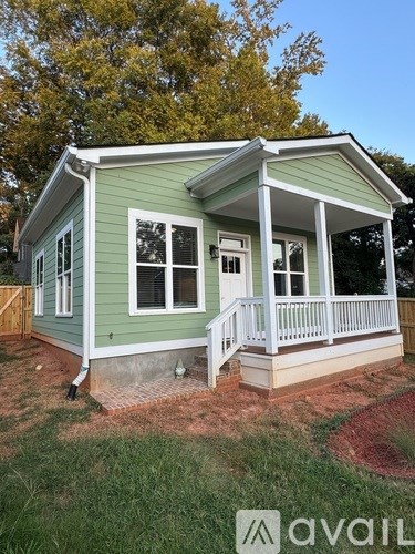A small house with a porch and a green exterior.