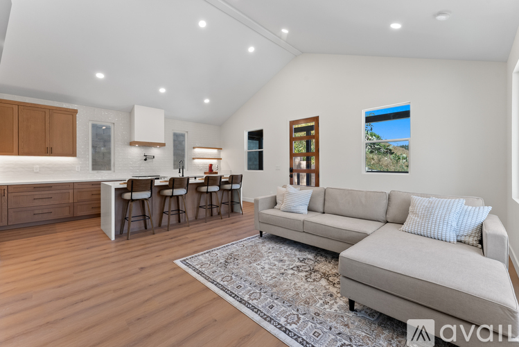 A spacious living room with a grey sofa and a bar area.