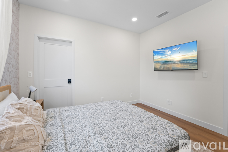 A bedroom with a large bed and a television mounted on the wall.