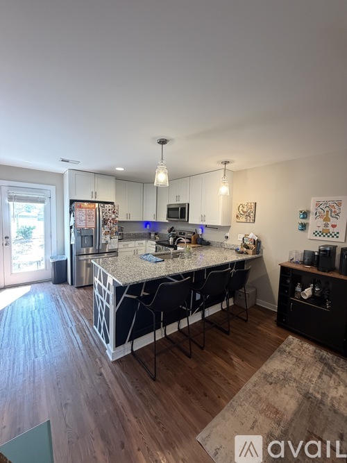 A kitchen with a large island and a dining table with chairs.