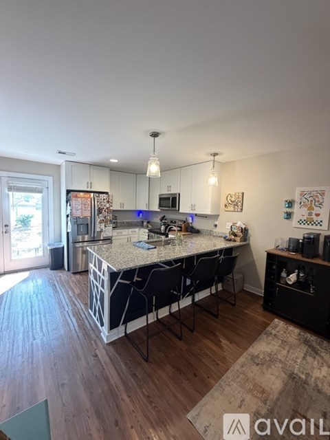 A kitchen with a large island and a dining table with chairs.