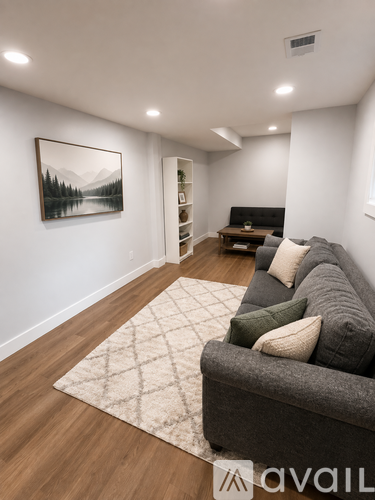 A living room with a grey couch and a painting on the wall.