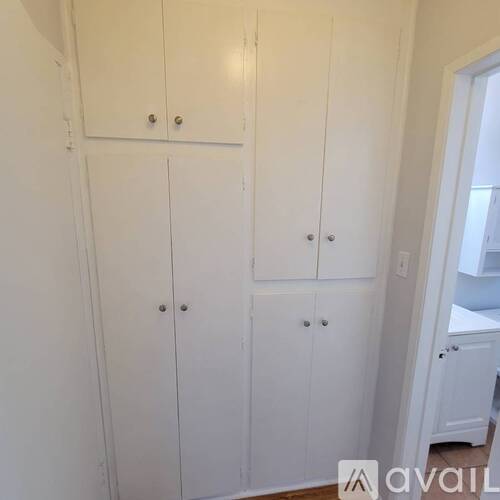 A set of white cupboards with silver handles.