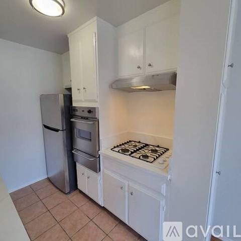 A kitchen with white cabinets and a stove top oven.