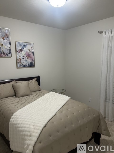 A bedroom with a large bed and a floral picture on the wall.