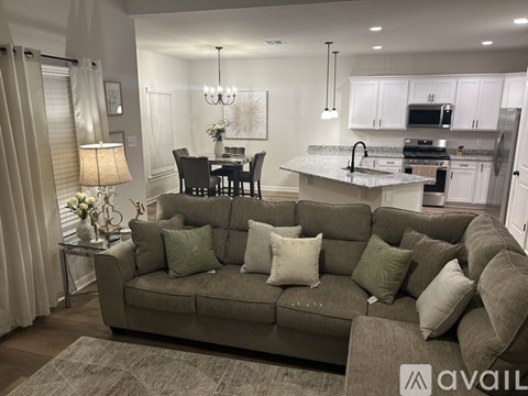 A living room with a grey couch and a dining table.