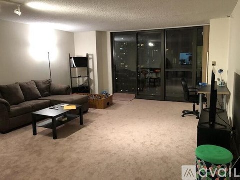 A living room with a brown couch, a coffee table, and a green stool.