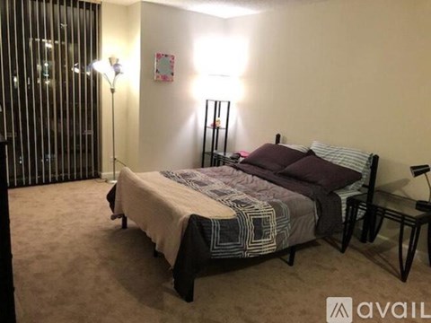 A bedroom with a bed, two lamps, and a chair.