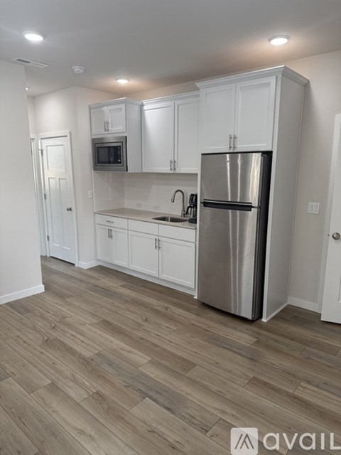A kitchen with white cabinets and a stainless steel refrigerator.