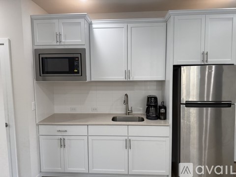 A kitchen with white cabinets and a stainless steel refrigerator.