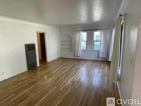 A room with wooden flooring and a black speaker on the left side.