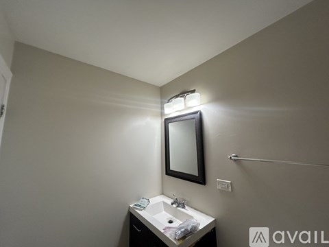 A bathroom with a sink, mirror, and light fixture.