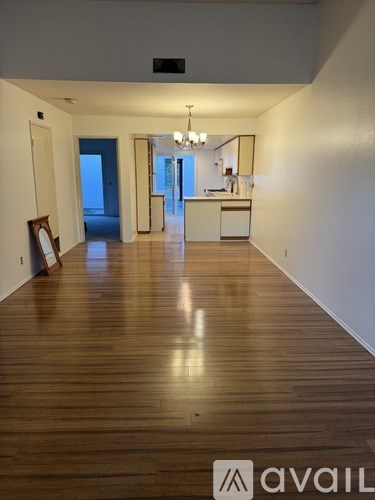 A long hallway with wood floors and a chandelier.