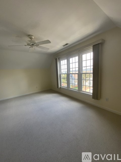 A room with a ceiling fan and a window with a view of a building outside.
