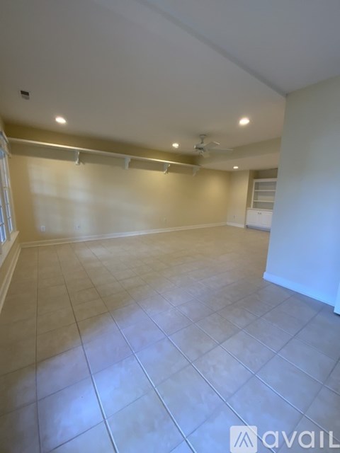 A spacious room with tiled flooring and a ceiling fan.