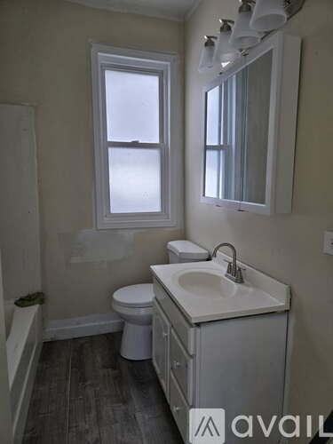 A bathroom with a toilet, sink, and mirror.