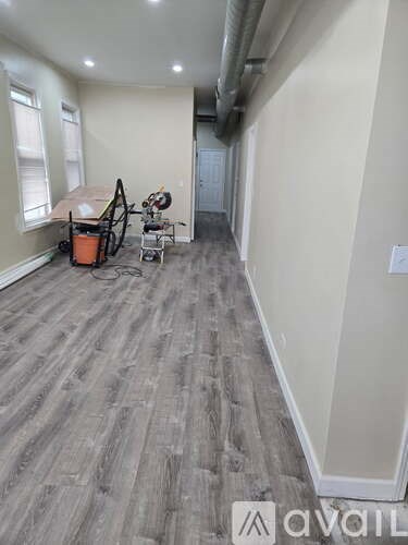 A room with a grey floor and a white wall with a door in the background.
