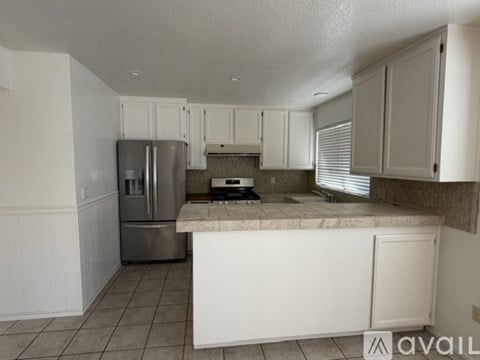 A kitchen with white cabinets and a marble countertop.