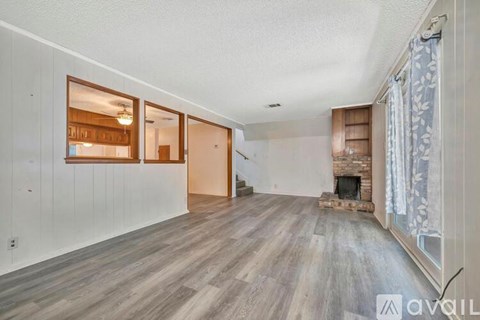 A spacious room with wooden floors and a fireplace.