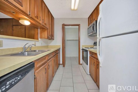 A kitchen with wooden cabinets and a black dishwasher.