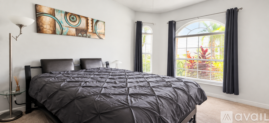 A bedroom with a large bed and a painting on the wall.