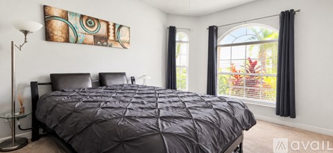 A bedroom with a large bed and a painting on the wall.
