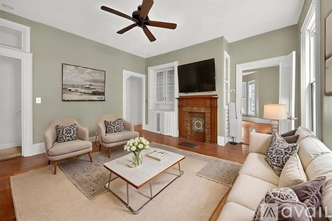 A living room with a fan, two chairs, a sofa, and a coffee table.