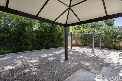A patio with a white umbrella and a playground in the background.