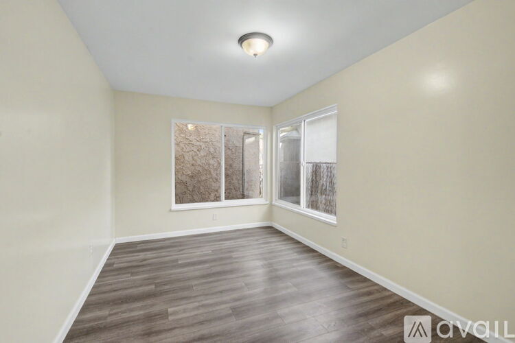 A spacious room with wood flooring and a large window.