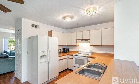 A kitchen with white appliances and wooden floors.