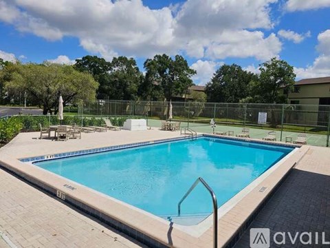 A large outdoor swimming pool surrounded by a fence and trees.