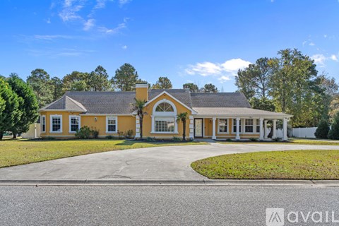 A yellow house with a grey roof and a white fence.